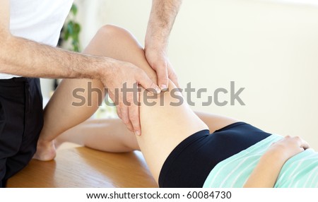 Caucasian young physical therapist giving a leg massage in a health center
