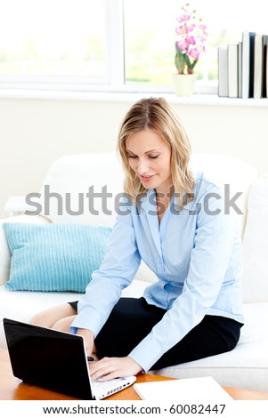 Serious businesswoman using her laptop on a sofa at home