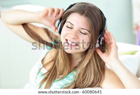 Delighted woman listening to music with headphones on a sofa at home