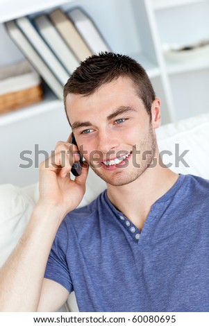 Happy young man talking on phone sitting on a sofa at home