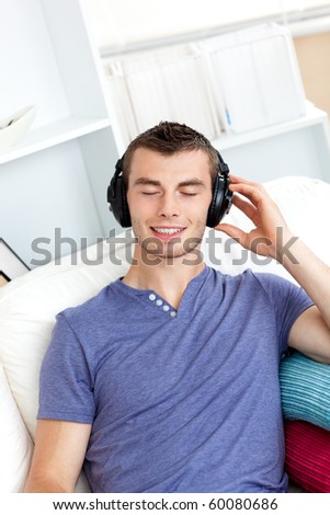 Relaxed young man listening to music sitting on the couch in the living-room at home