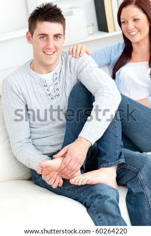 Nice boyfriend massaging his girlfriend\'s feet on the sofa at home