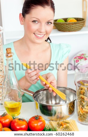 Charming woman cooking sphaghetti in the kitchen at home
