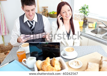 Busy couple of businesspeople having breakfast in the kitchen at home