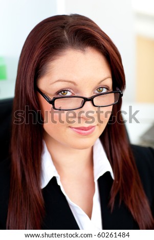 Self-assured businesswoman wearing glasses sitting in her office at her desk