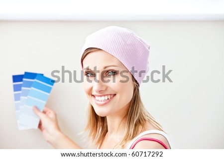 Joyful young woman choosing color for painting a room in her new house