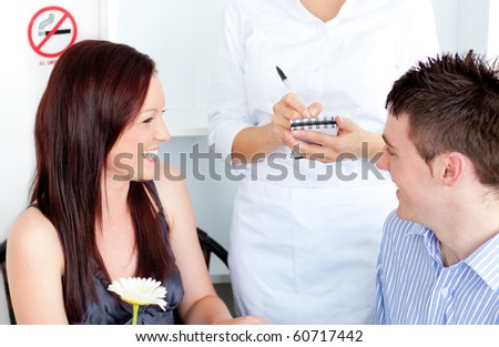 Joyful young couple dining at the restaurant with waiter taking order