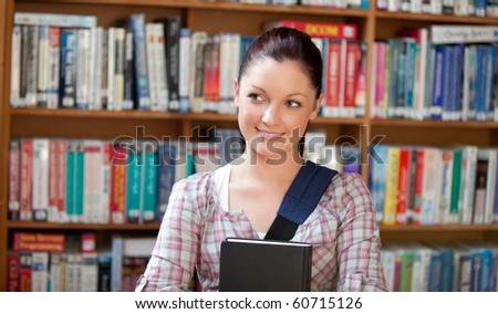 Joyful young caucasian woman holding a book in a book store