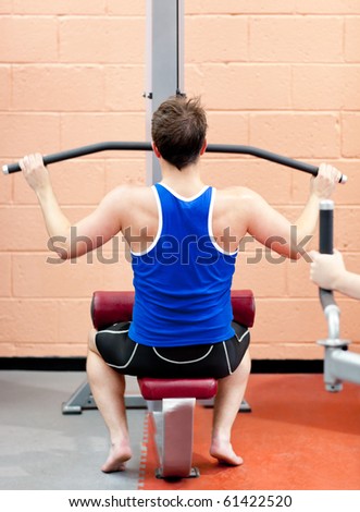 Assertive male athlete practicing body-building in a fitness center