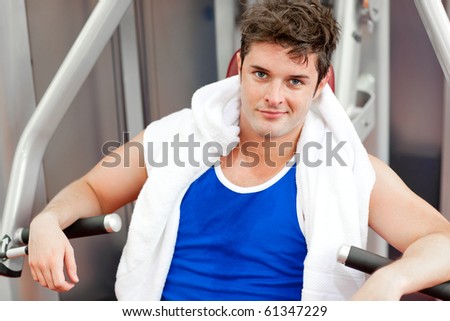Confident young man with a towel using a bench press in a fitness center