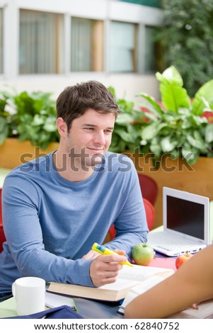 Portrait of a confident student working with his friend in the cafeteria of their university