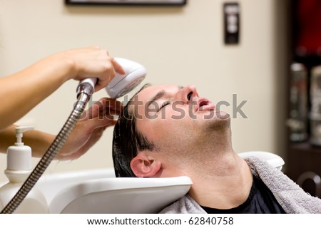 Young caucasian man having his hair washed in a hairdressing salon