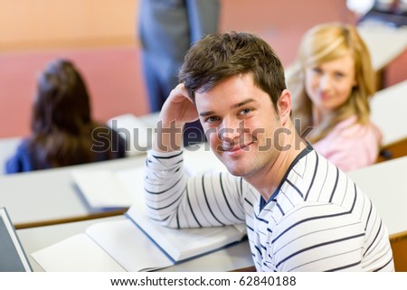 Joyful male student smiling at the camera during an university lesson in an auditorium