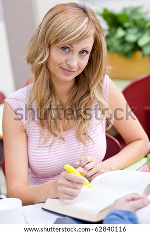 Portrait of a concentrated female student working with a friend in the cafeteria of their university