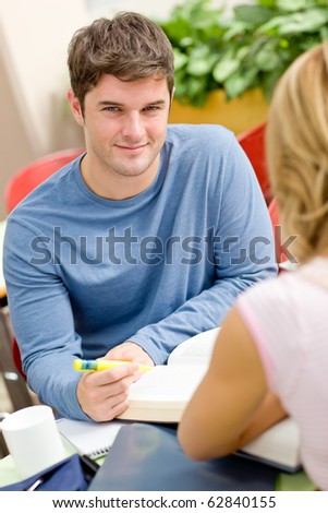 Portrait of a self-assured student working with his friend in the cafeteria of their university