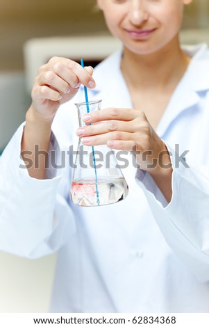Portrait of a female scientist shaking liquid in an erlenmeyer in her laboratory