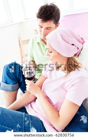 Happy couple drinking wine on the sofa after painting their new room in their new house