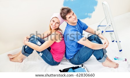 Smiling young couple relaxing after painting a room in their new house