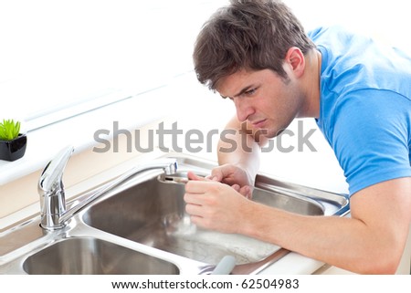 Concentrated man repairing his sink in the kitchen at home