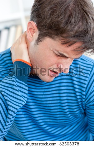 Caucasian man having a neck ache in the living-room at home