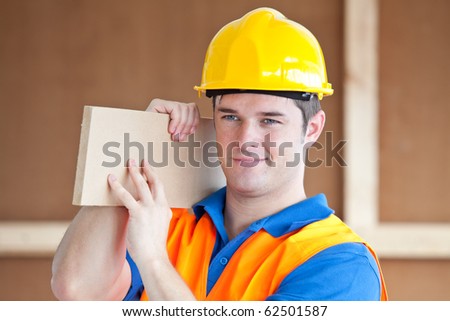 Young male worker carrying a wooden board at work