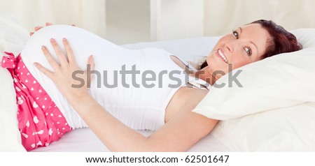 Radiant pregnant woman resting n her bed in the bedroom at home