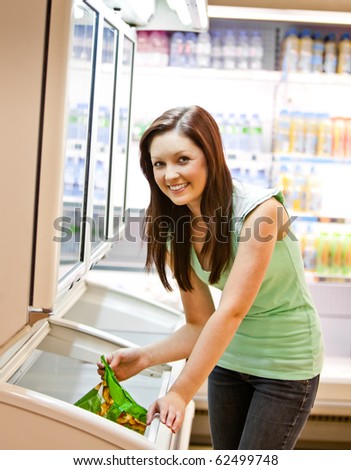 Smiling young woman holding a deep-frozen product in a supermarket