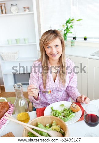 Beautiful woman eating salad in the kitchen at home