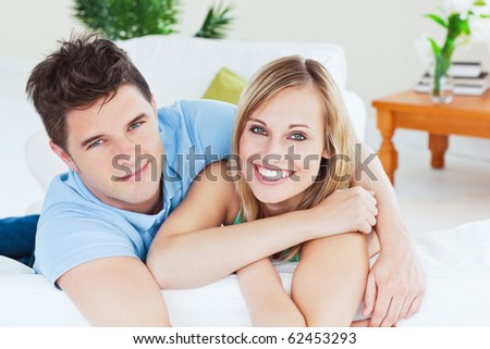 Smiling beautiful couple sitting on a sofa looking at the camera