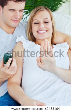 Joyful woman looking at a wedding ring after a proposal at home