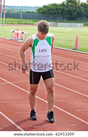 Focused sprinter ready to run standing on the starting line in a stadium