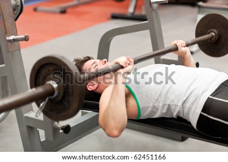 Muscular young man using weightlifting lying in a fitness center