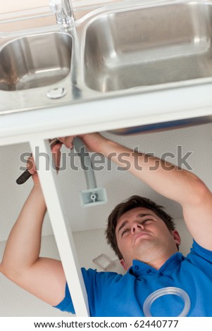 Plumber making efforts to repair a sink lying on the floor in the kitchen