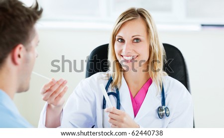 Attractive female doctor taking patient\'s temperature smiling at the camera  in her office