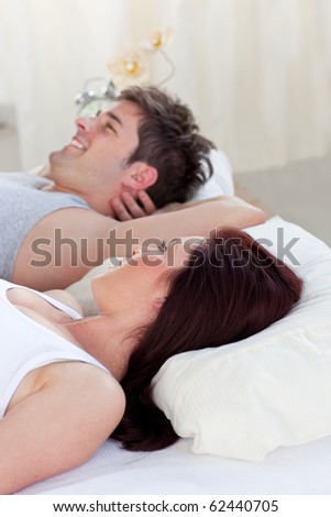 Portrait of a happy man lying on the bed with his pregnant woman during the morning