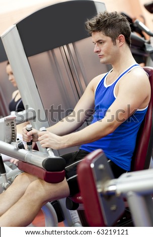 Serious athletic man using a leg press  in the weights room of a sport centre