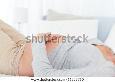 Close up of a future mom lying on the bed and touching her belly