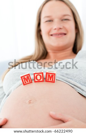 Close up of a woman having mom letters on her belly lying on a bed at home