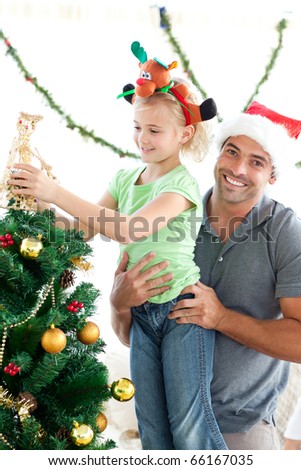 Proud dad helping his little girl to decorate the christmas tree at home