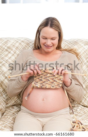 Cute future mother knitting sitting on the sofa at home