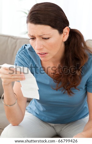 Nervous woman looking at a bill while doing her accounts at home