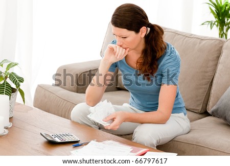 Stressed woman calculating her bills sitting on the sofa at home