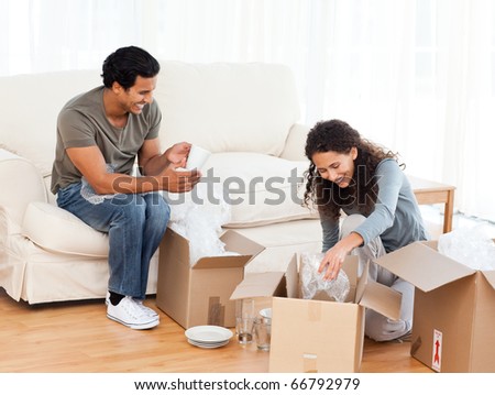 Happy couple packing glasses together in the living-room for their removal