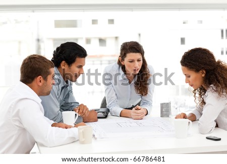 Four charismatic architects looking at plans together around a table