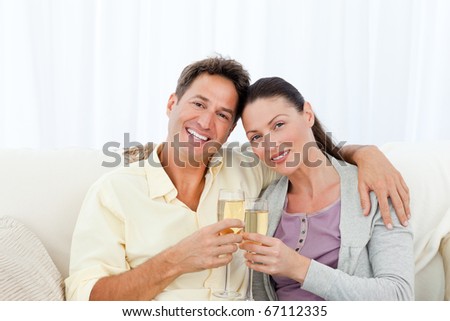 Portrait of a couple holding flutes of champagne on the sofa at home