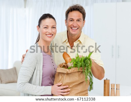 Portrait of a couple coming back from the market with vegetables and bread