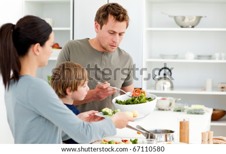 Dad serving salad to his family for lunch in the kitchen