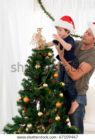 Cute son decorating the christmas tree with his father in the living room
