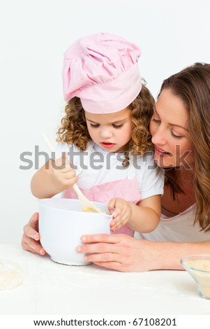 Cute girl  preparing a cake with her mother in the kitchen