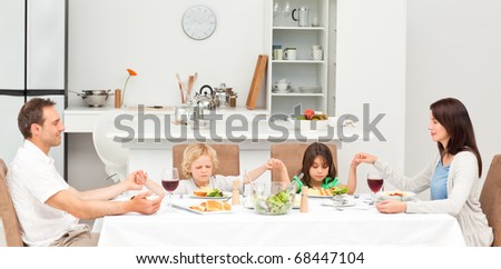 Concentrated family praying before having lunch in the kitchen